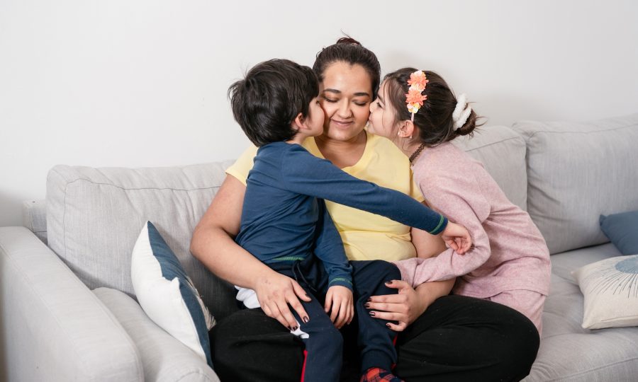 Mother and two kids sitting on sofa at home